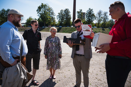 Czterech mężczyzn i jedna kobieta stoją na brukowanej nawierzchni i rozmawiają.